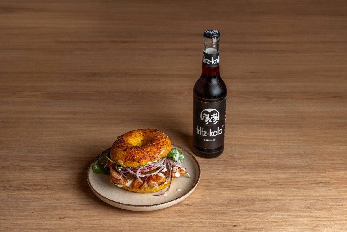 Belegter Sauerteig-Bagel mit einer Flasche Cola
